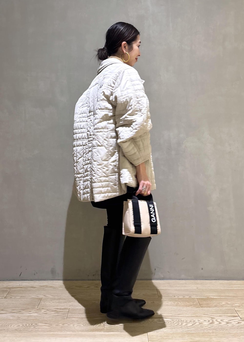 ベージュ系のトートバッグ、ブラック系のブーツ、ブラック系のスカートを着用したレディースの冬コーディネートの5枚目の写真