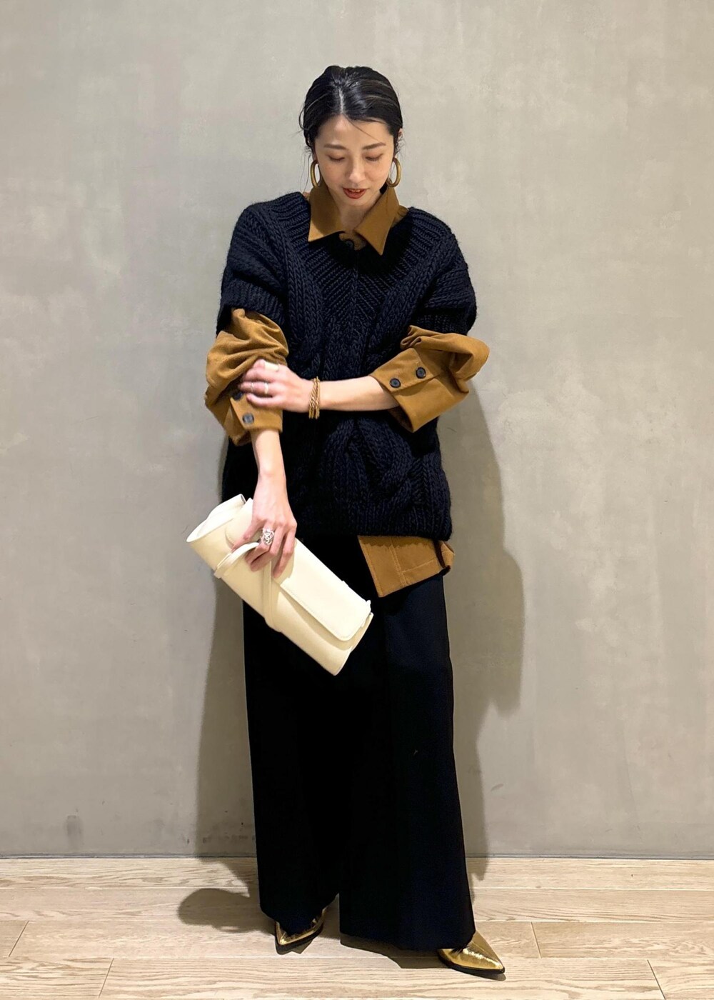 ブラック系のニット/セーター、ゴールド系のブーツ、イエロー系のブルゾンを着用したレディースの秋コーディネートの7枚目の写真