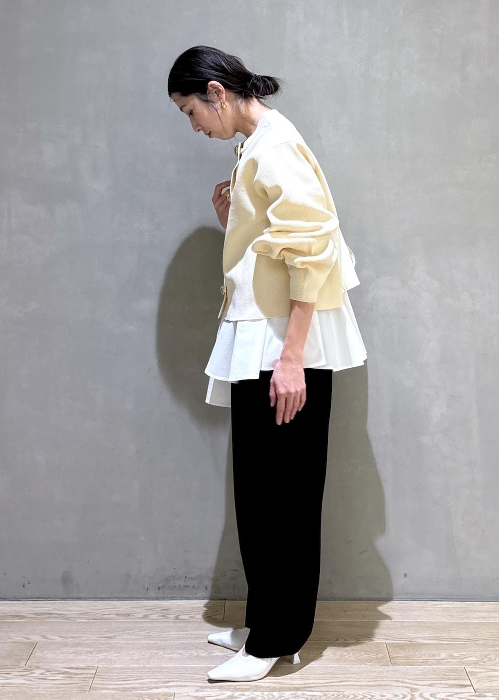 ホワイト系のパンプス、ブラック系のスラックス、ホワイト系のショルダーバッグを着用したレディースの冬コーディネートの5枚目の写真