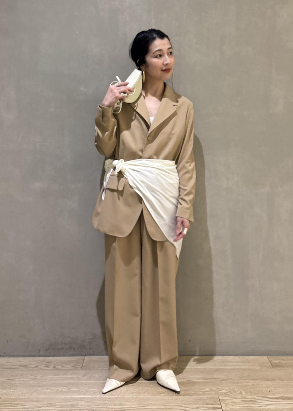 ベージュ系のテーラードジャケット、ホワイト系のシャツ/ブラウス、ベージュ系のスラックスを着用したレディースの冬コーディネートの7枚目の写真