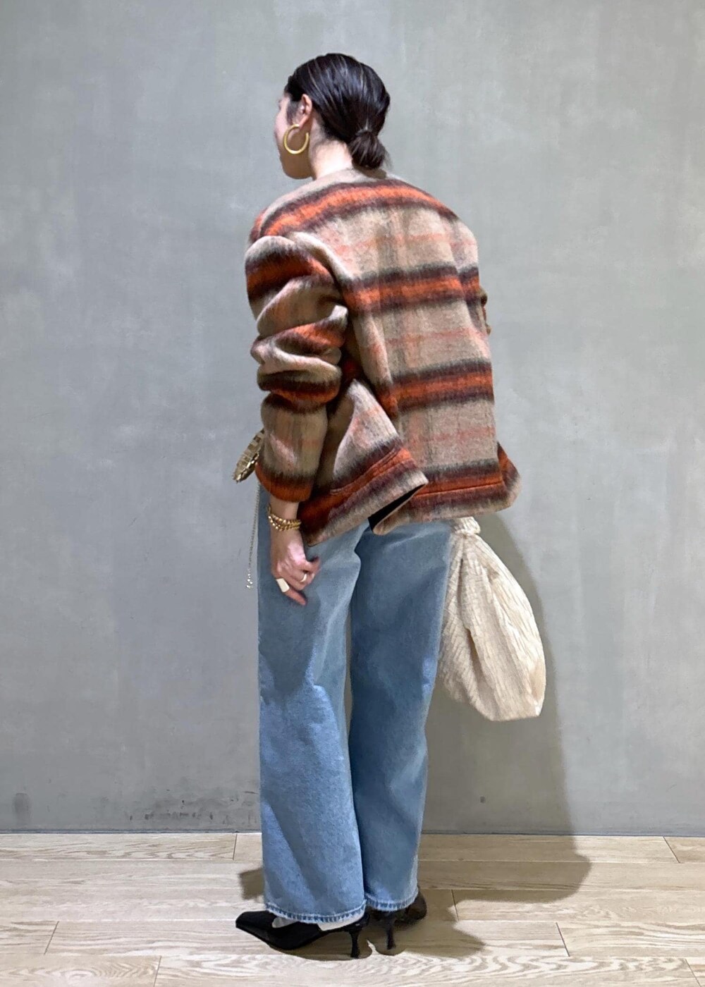 ホワイト系のハンドバッグ、ゴールド系のショルダーバッグ、ブルー系のデニムパンツを着用したレディースの冬コーディネートの5枚目の写真