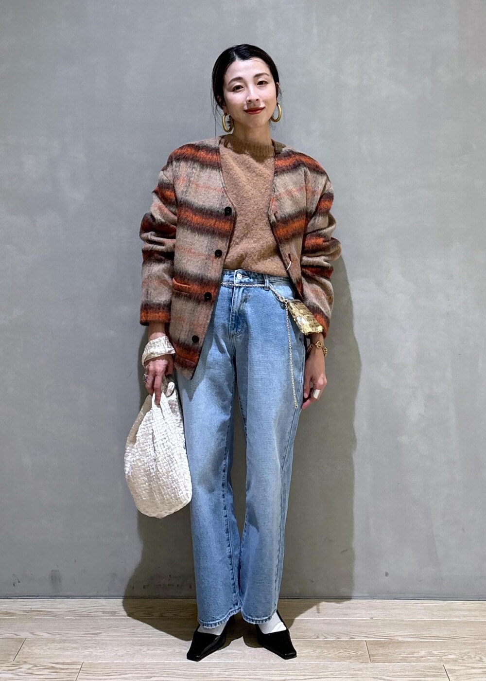 ホワイト系のハンドバッグ、ゴールド系のショルダーバッグ、ブルー系のデニムパンツを着用したレディースの冬コーディネートの6枚目の写真