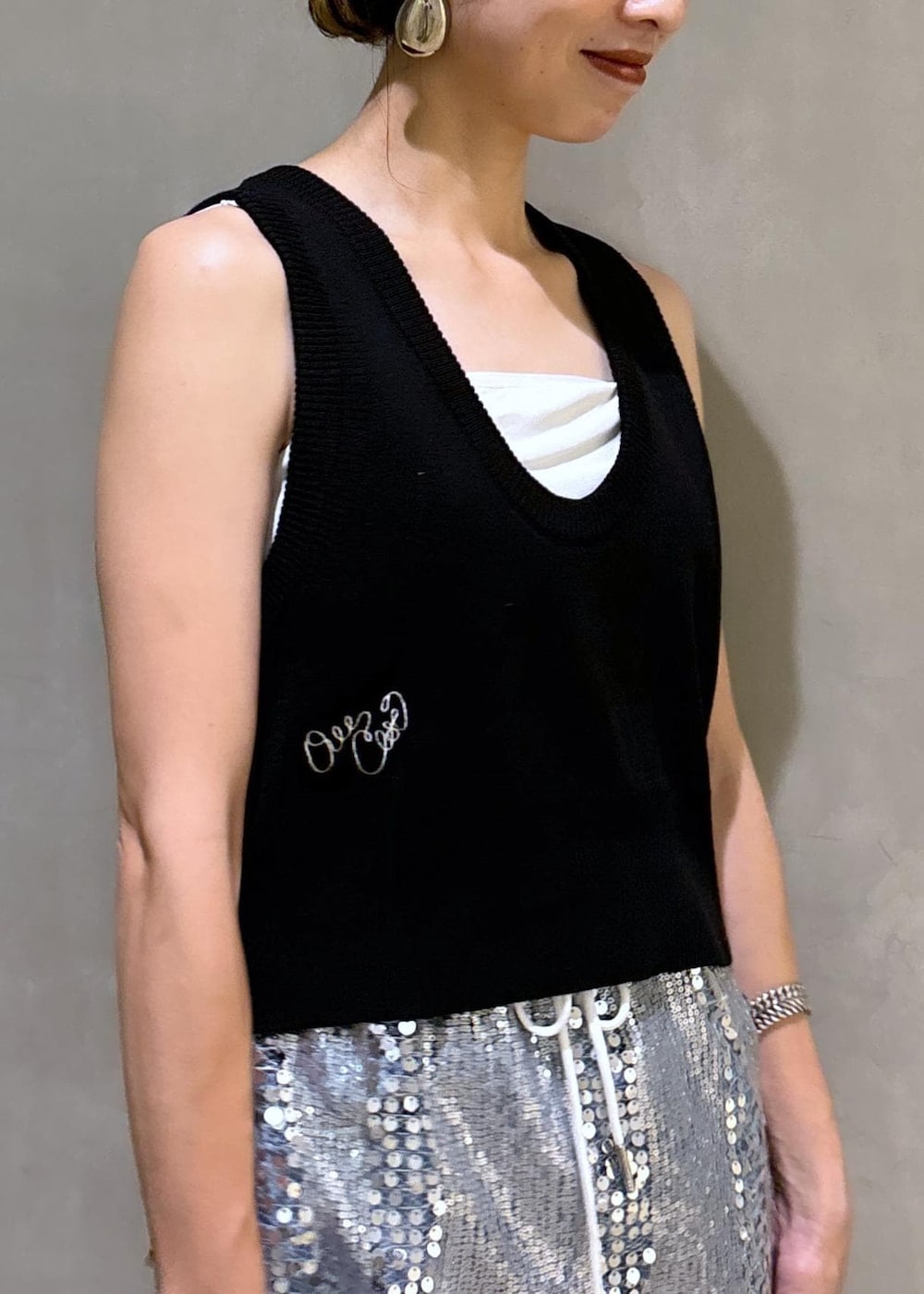 シルバー系のスカート、ブラック系のベスト、ブルー系のデニムパンツを着用したレディースの夏コーディネートの9枚目の写真