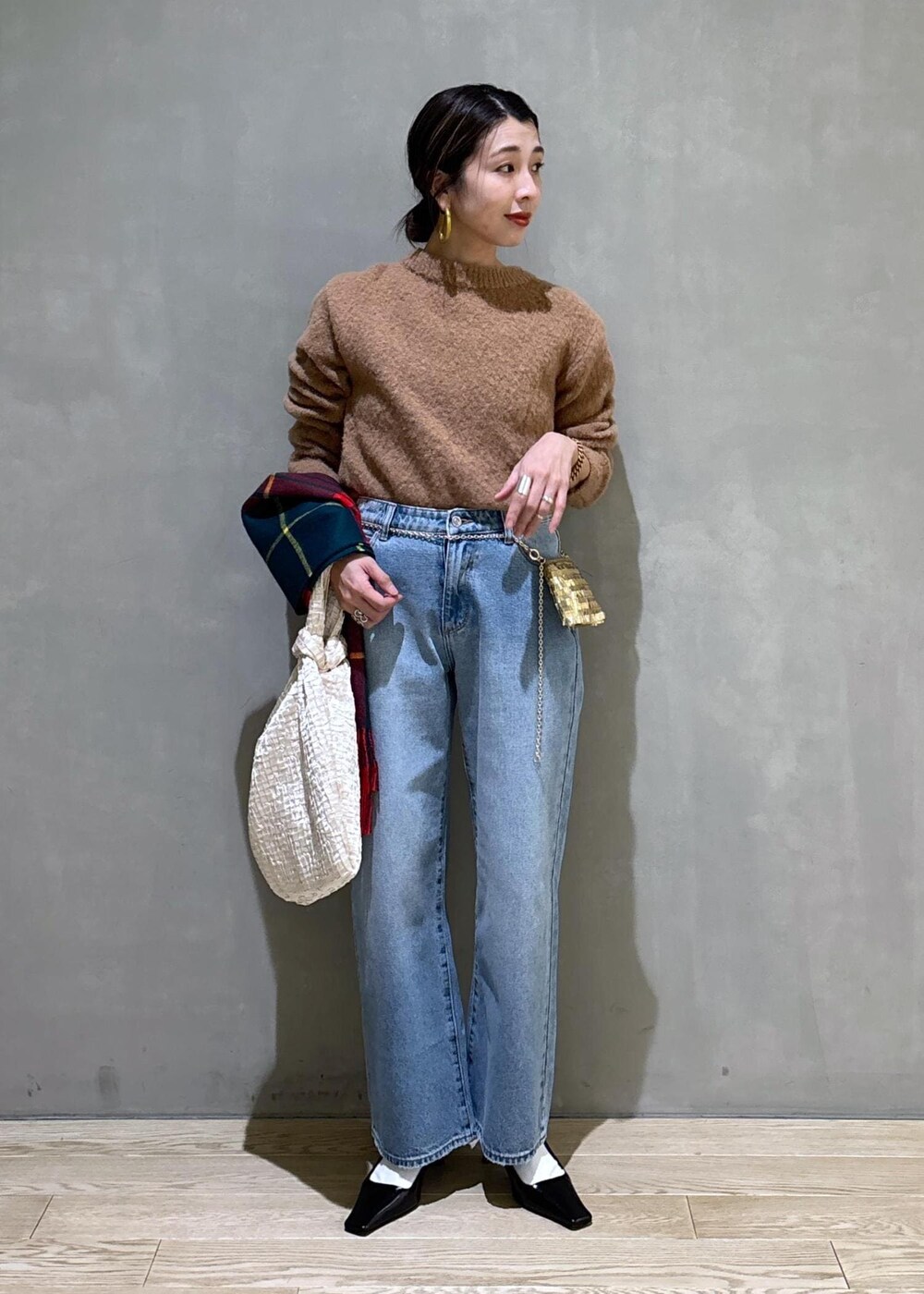 ホワイト系のハンドバッグ、ゴールド系のショルダーバッグ、ブルー系のデニムパンツを着用したレディースの冬コーディネートの7枚目の写真