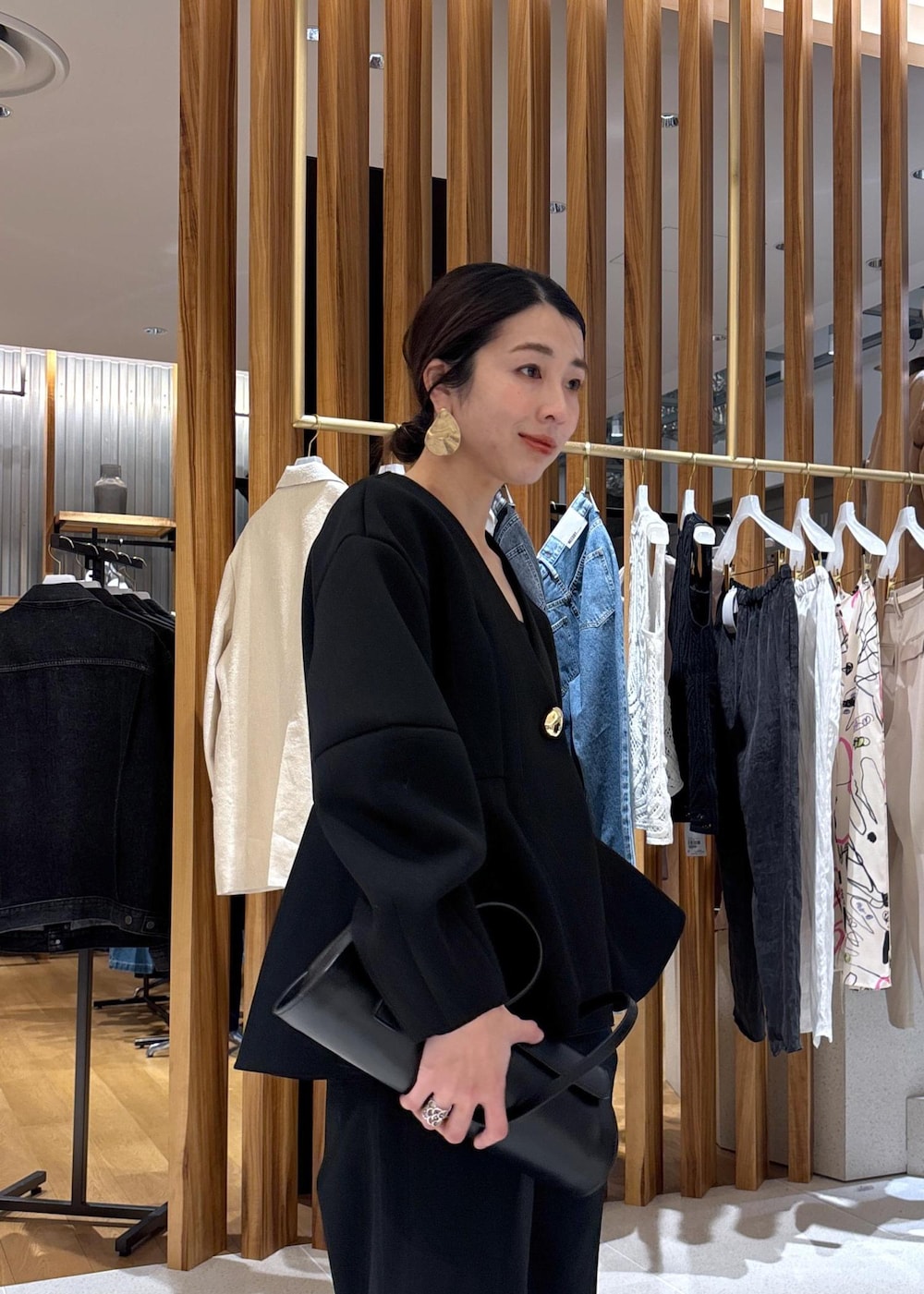 ブラック系のショルダーバッグ、ホワイト系のパンプス、ブラック系のスラックスを着用したレディースの冬コーディネートの8枚目の写真
