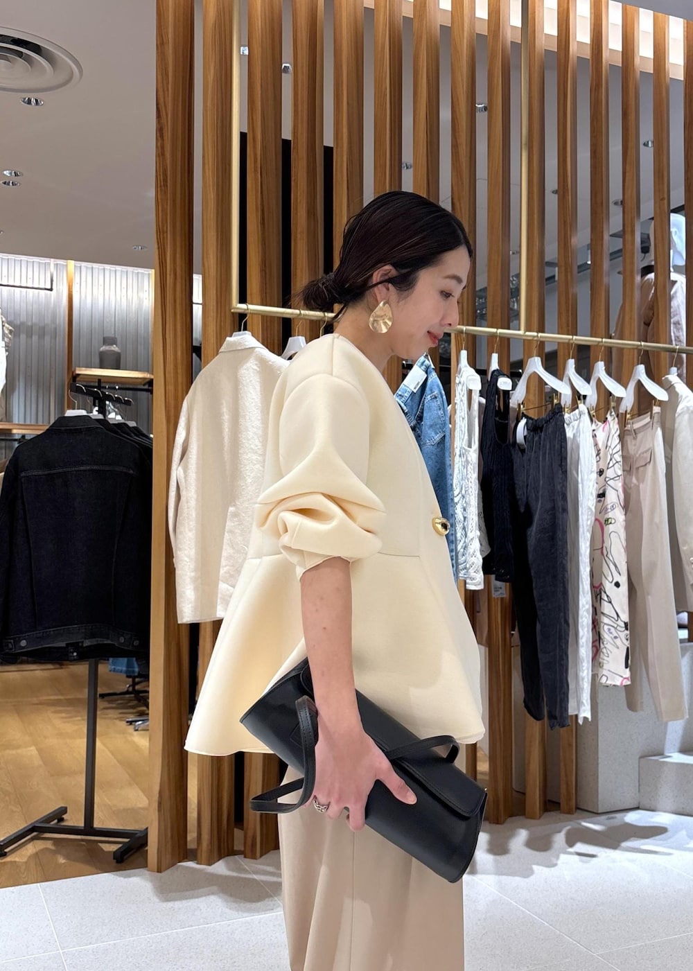 ブラック系のショルダーバッグ、ホワイト系のパンプス、ベージュ系のスラックスを着用したレディースの冬コーディネートの9枚目の写真