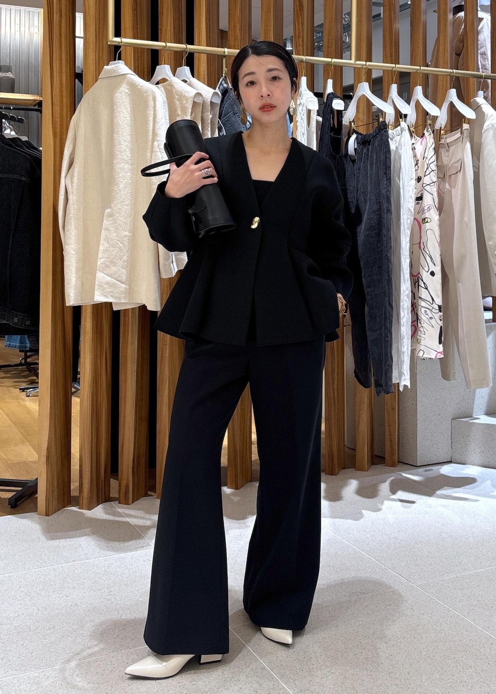 ブラック系のショルダーバッグ、ホワイト系のパンプス、ブラック系のスラックスを着用したレディースの冬コーディネートの3枚目の写真
