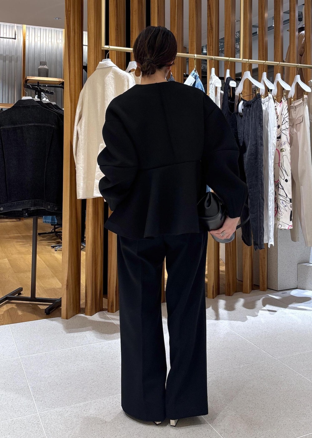 ブラック系のショルダーバッグ、ホワイト系のパンプス、ブラック系のスラックスを着用したレディースの冬コーディネートの5枚目の写真