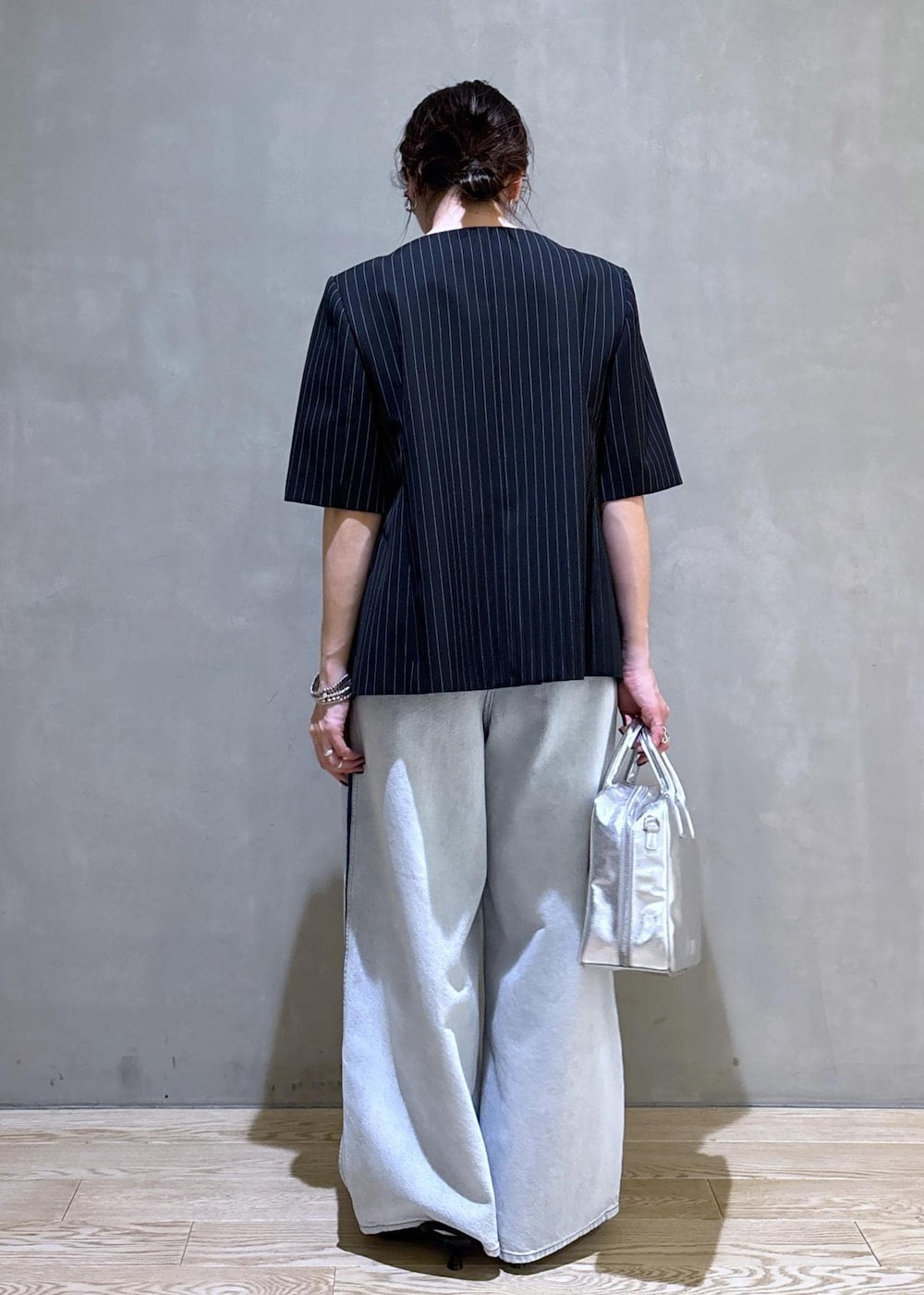 ブルー系のデニムパンツ、ブラック系のノーカラージャケット、シルバー系のボストンバッグを着用したレディースの春コーディネートの7枚目の写真