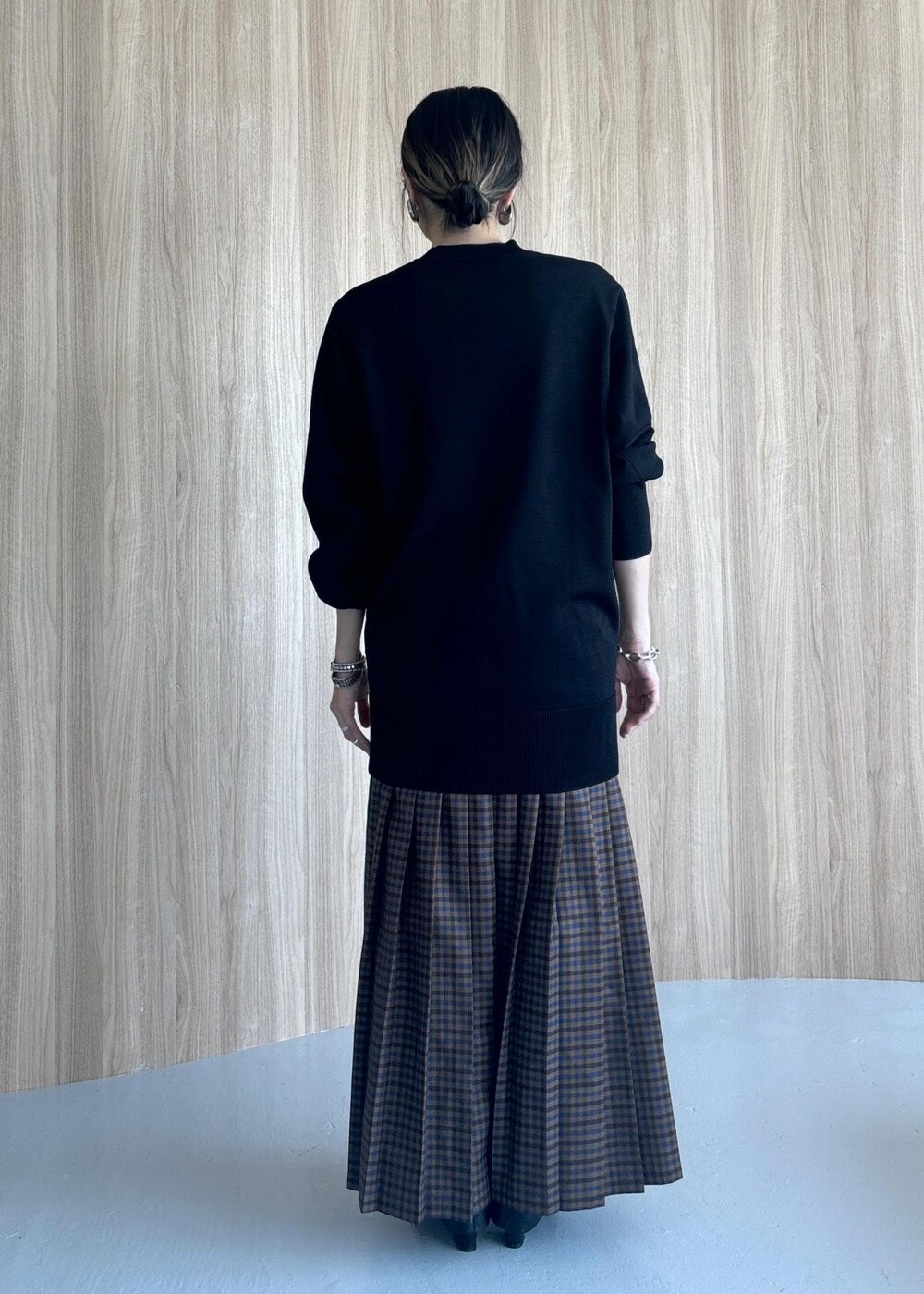 グレー系のスカート、ブラック系のブーツ、ブラック系のニット/セーターを着用したレディースの秋コーディネートの5枚目の写真