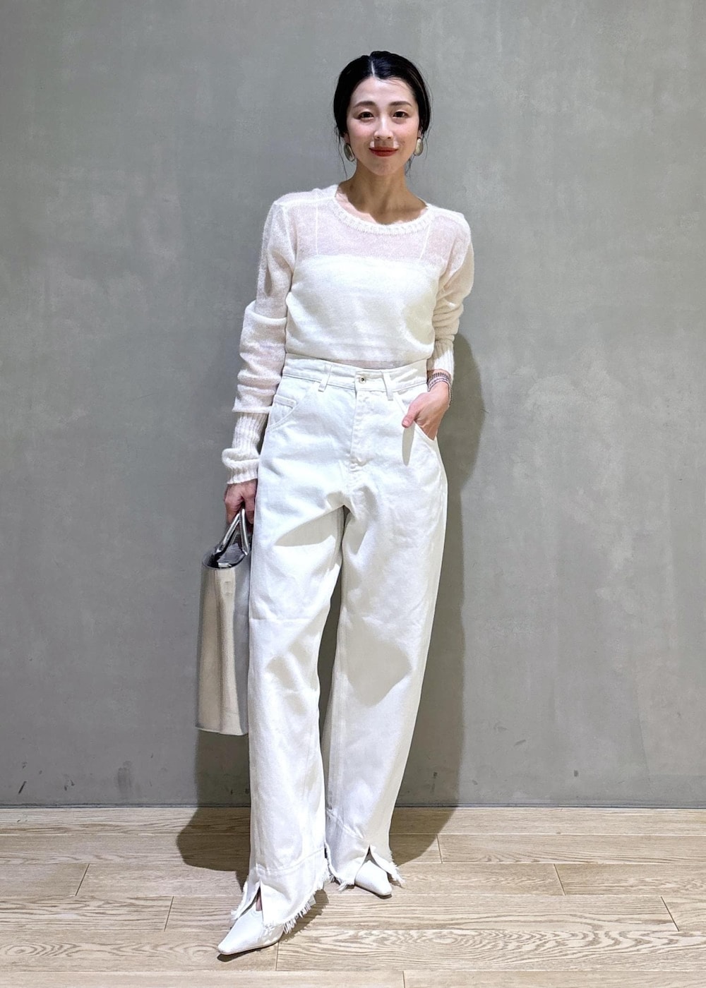 ホワイト系のパンプス、シルバー系のトートバッグ、ホワイト系のデニムパンツを着用したレディースの冬コーディネートの5枚目の写真