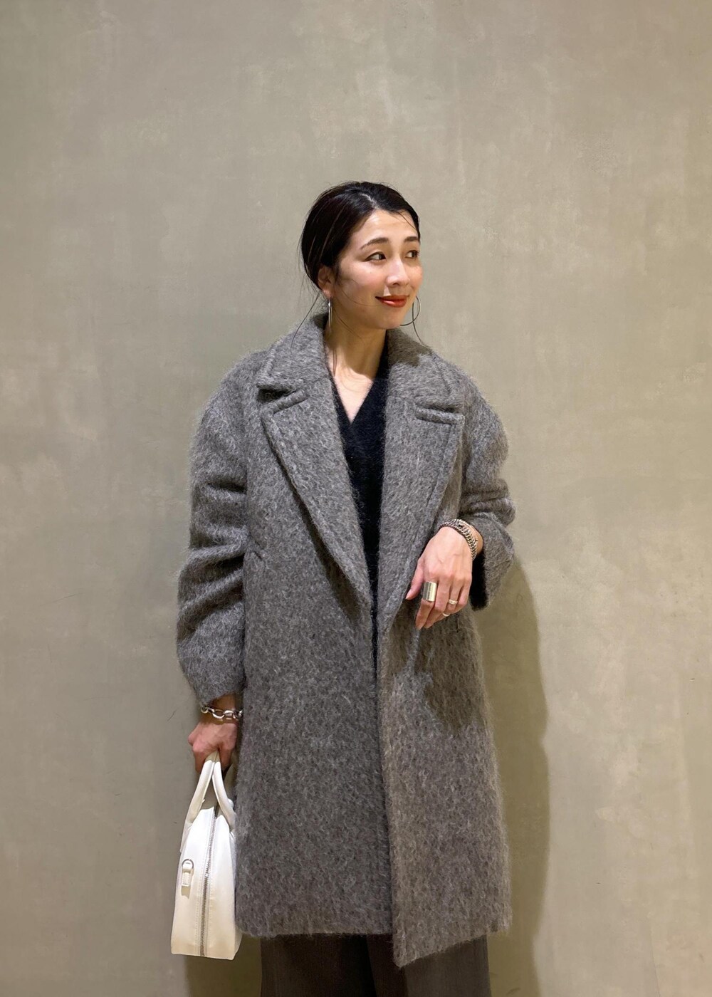 ホワイト系のボストンバッグ、グレー系のカーディガン/ボレロ、グレー系のチェスターコートを着用したレディースの秋コーディネートの8枚目の写真