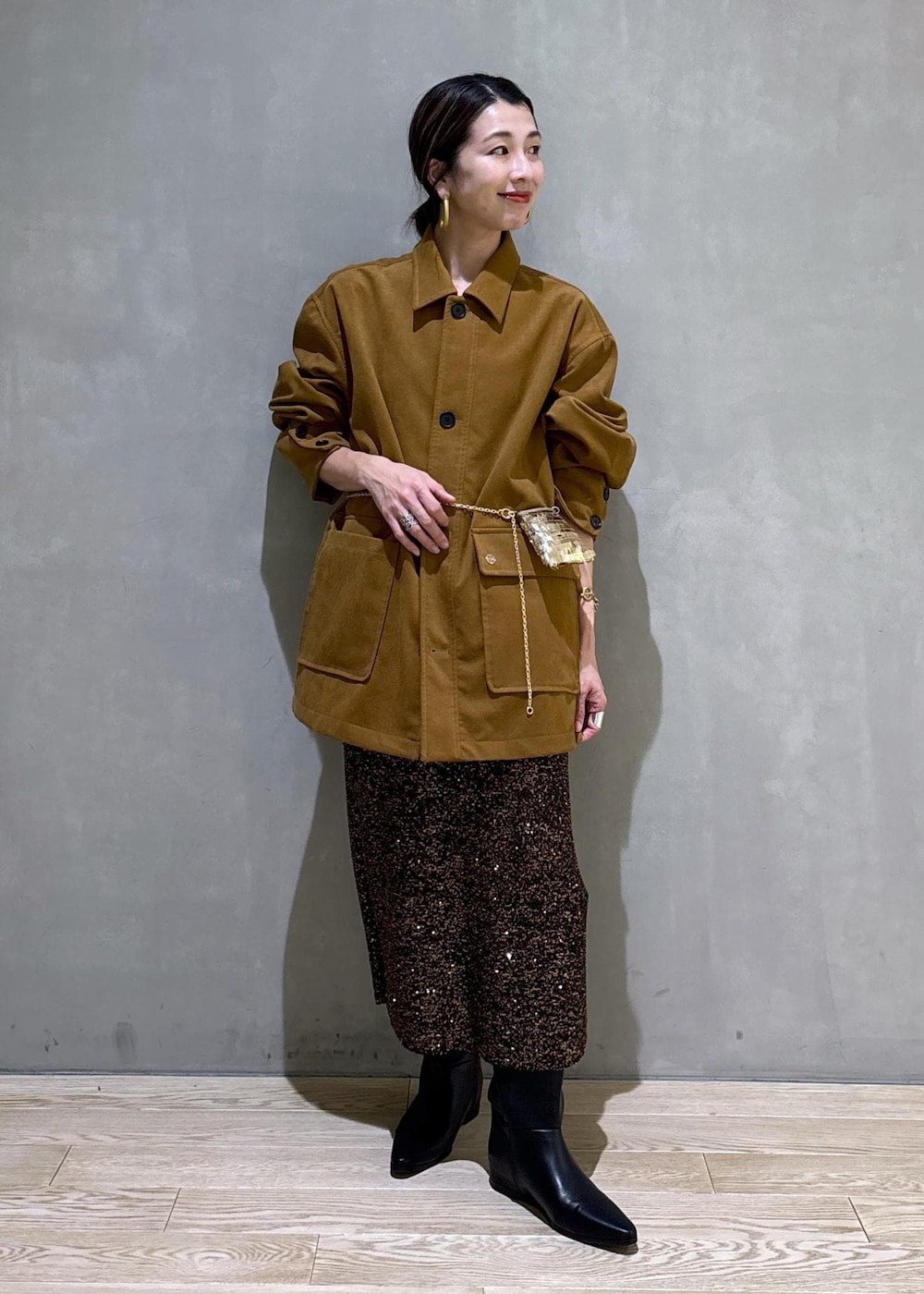 ブラック系のブーツ、ブラック系のスカート、イエロー系のブルゾンを着用したレディースの冬コーディネートの3枚目の写真