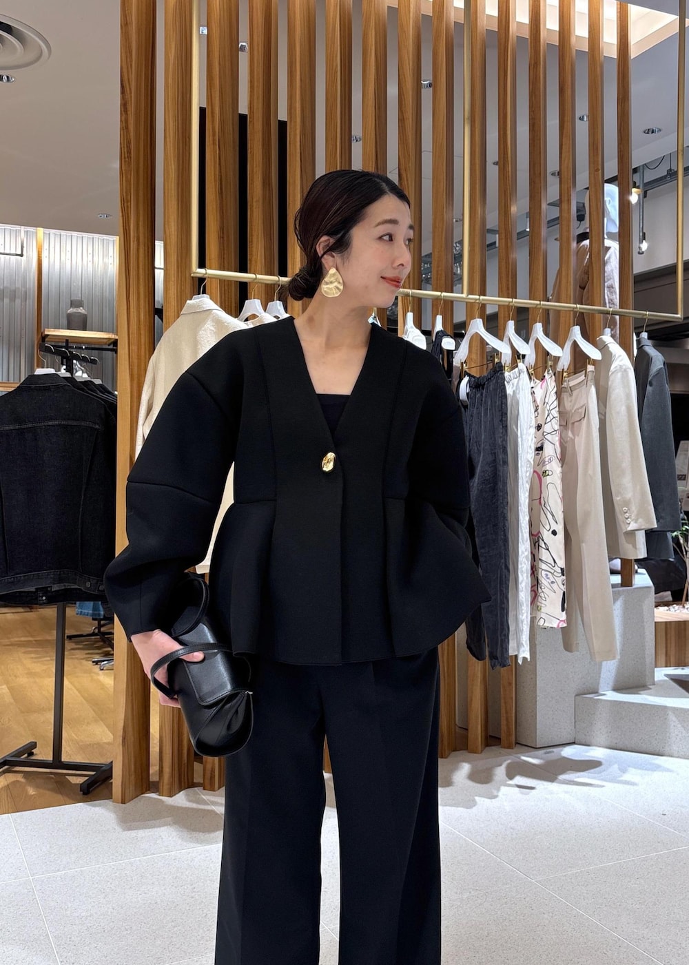 ブラック系のショルダーバッグ、ホワイト系のパンプス、ブラック系のスラックスを着用したレディースの冬コーディネートの10枚目の写真