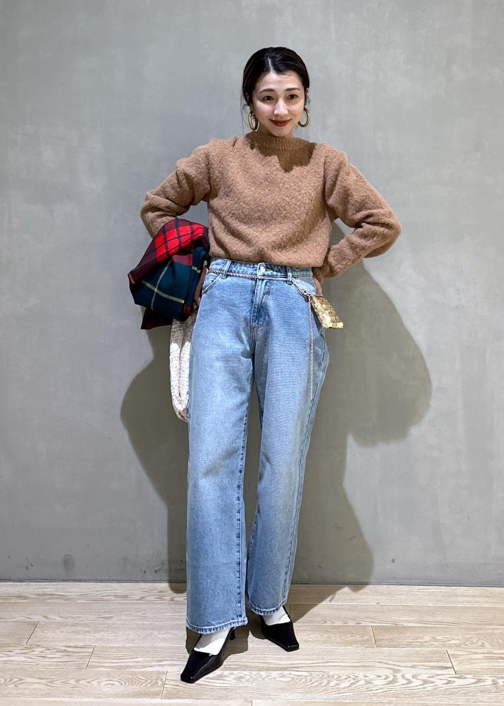 ホワイト系のハンドバッグ、ゴールド系のショルダーバッグ、ブルー系のデニムパンツを着用したレディースの冬コーディネートの3枚目の写真