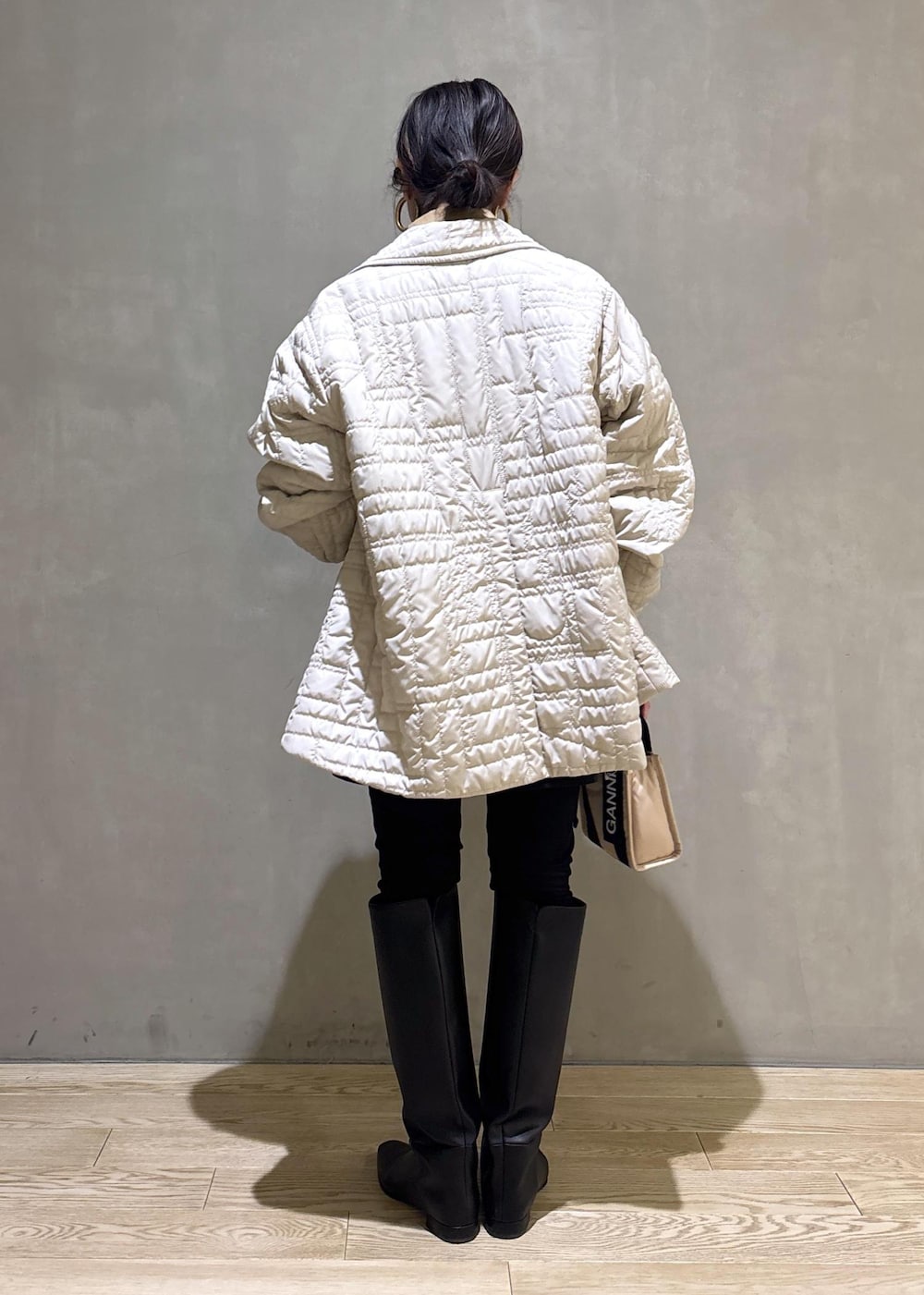 ベージュ系のトートバッグ、ブラック系のブーツ、ブラック系のスカートを着用したレディースの冬コーディネートの6枚目の写真