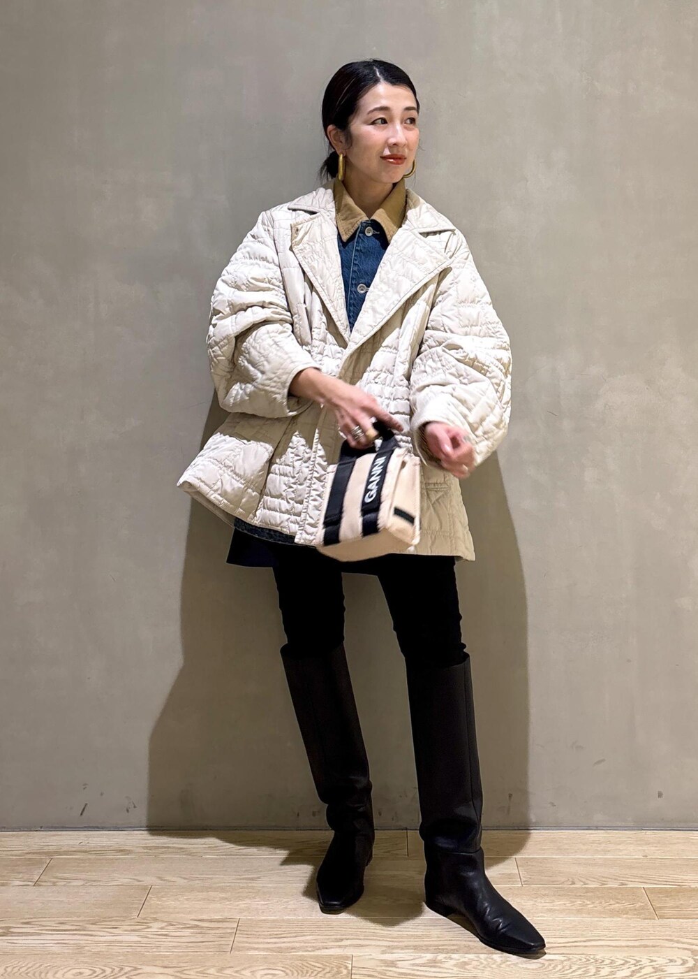 ベージュ系のトートバッグ、ブラック系のブーツ、ブラック系のスカートを着用したレディースの冬コーディネートの2枚目の写真