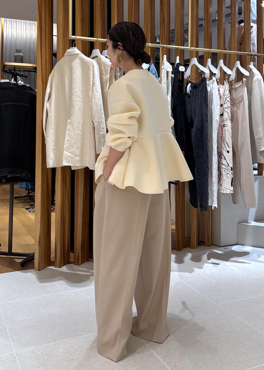 ブラック系のショルダーバッグ、ホワイト系のパンプス、ベージュ系のスラックスを着用したレディースの冬コーディネートの4枚目の写真