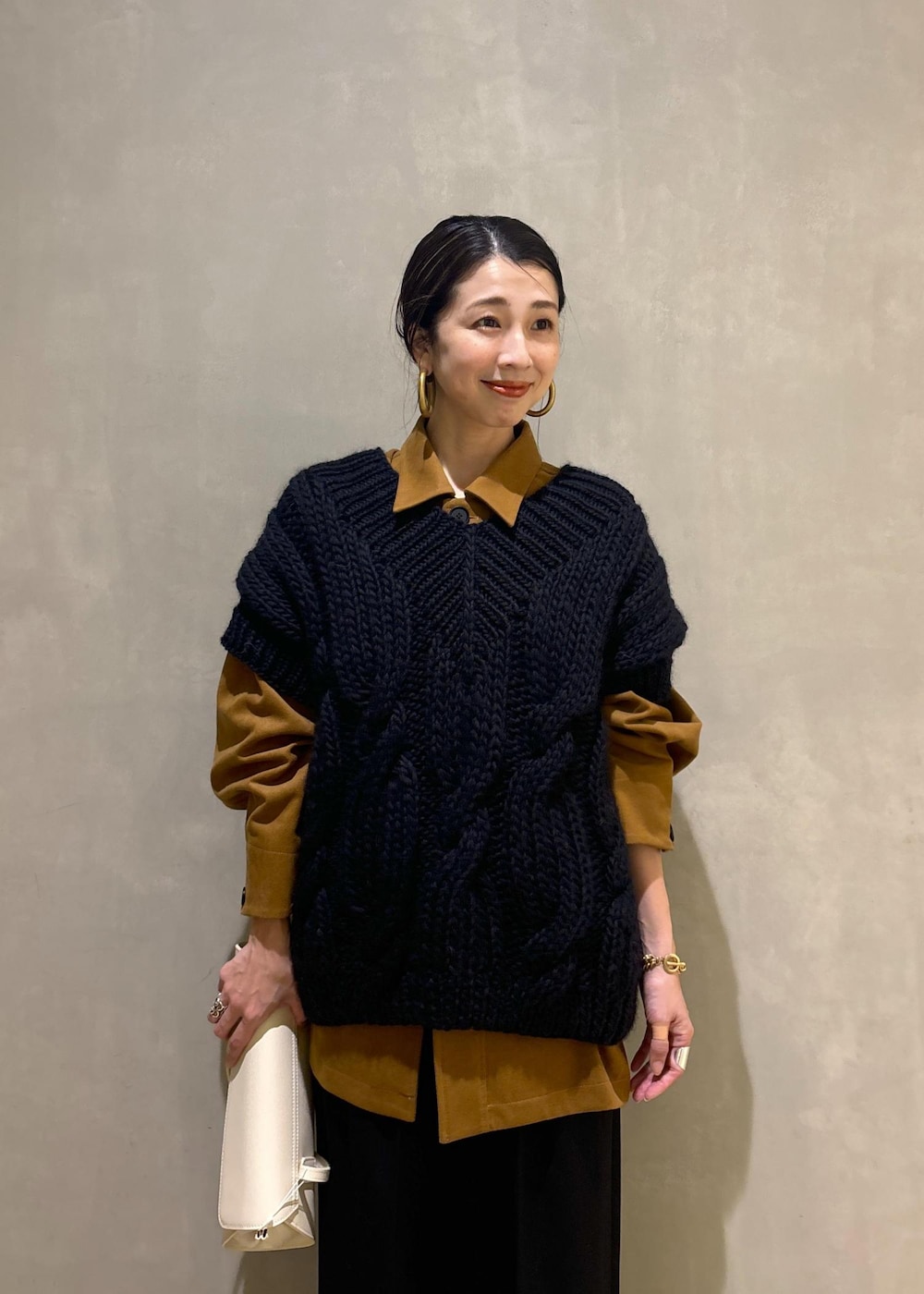 ブラック系のニット/セーター、ゴールド系のブーツ、イエロー系のブルゾンを着用したレディースの秋コーディネートの8枚目の写真