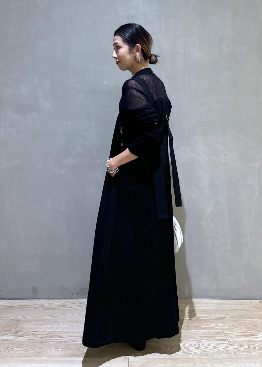 ホワイト系のボストンバッグ、ブラック系のワンピース、ブラック系のブーツを着用したレディースの秋コーディネートの6枚目の写真