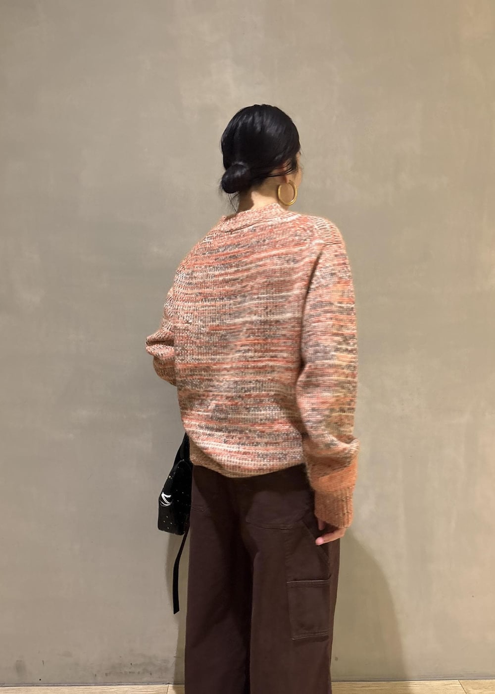 オレンジ系のニット/セーター、ブラック系のショルダーバッグ、ブラウン系のその他パンツを着用したレディースの秋コーディネートの10枚目の写真