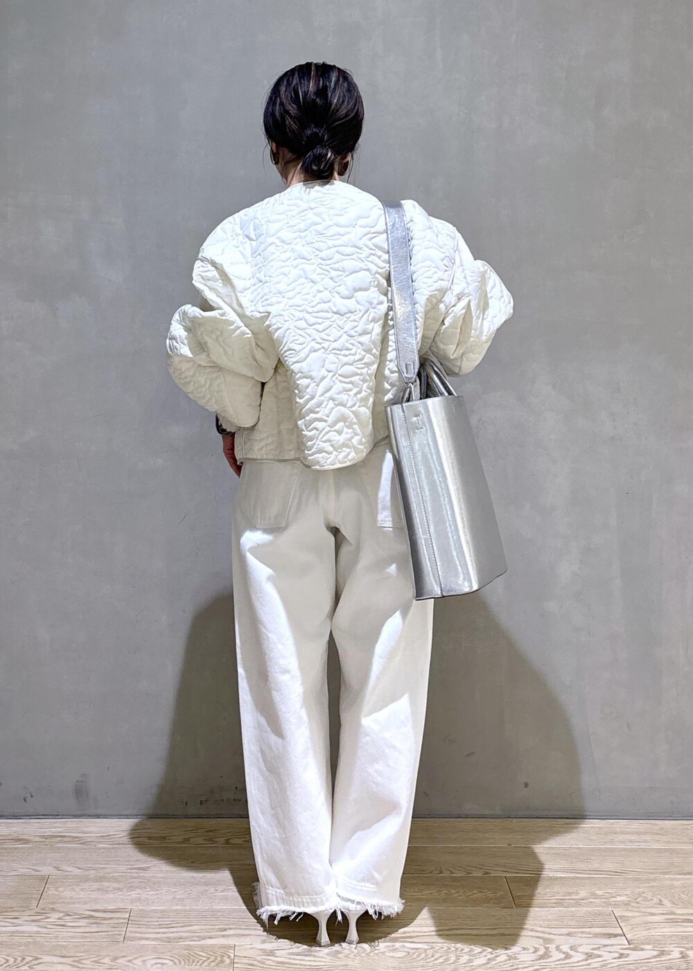 ホワイト系のパンプス、シルバー系のトートバッグ、ホワイト系のデニムパンツを着用したレディースの冬コーディネートの6枚目の写真