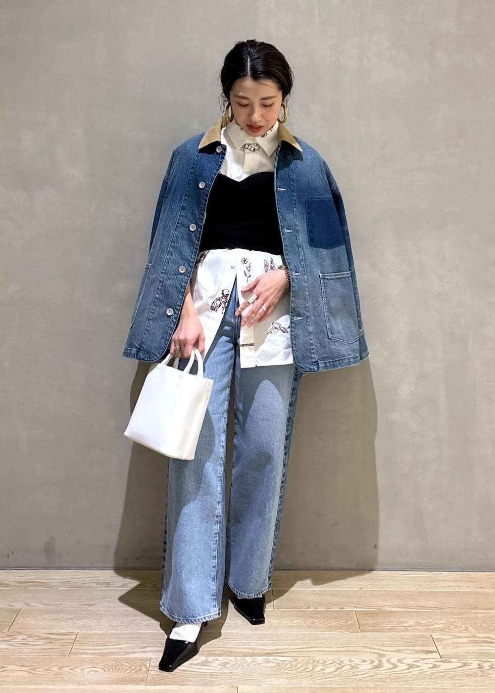 ホワイト系のハンドバッグ、ブルー系のデニムパンツ、ブルー系のデニムジャケットを着用したレディースの冬コーディネートの3枚目の写真