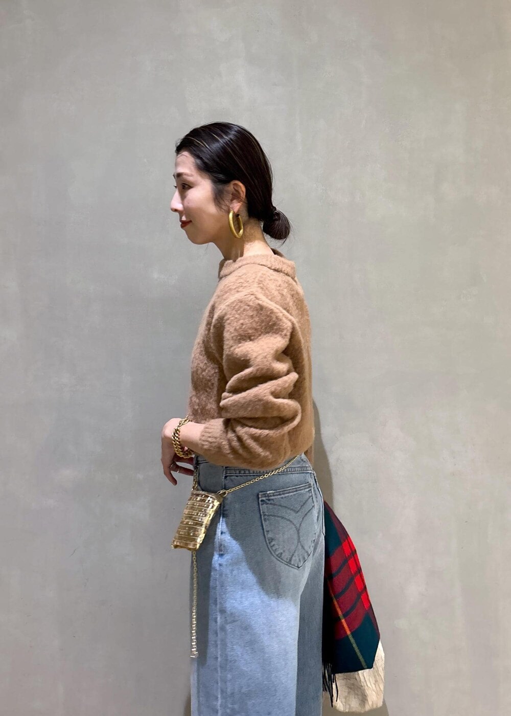 ホワイト系のハンドバッグ、ゴールド系のショルダーバッグ、ブルー系のデニムパンツを着用したレディースの冬コーディネートの10枚目の写真