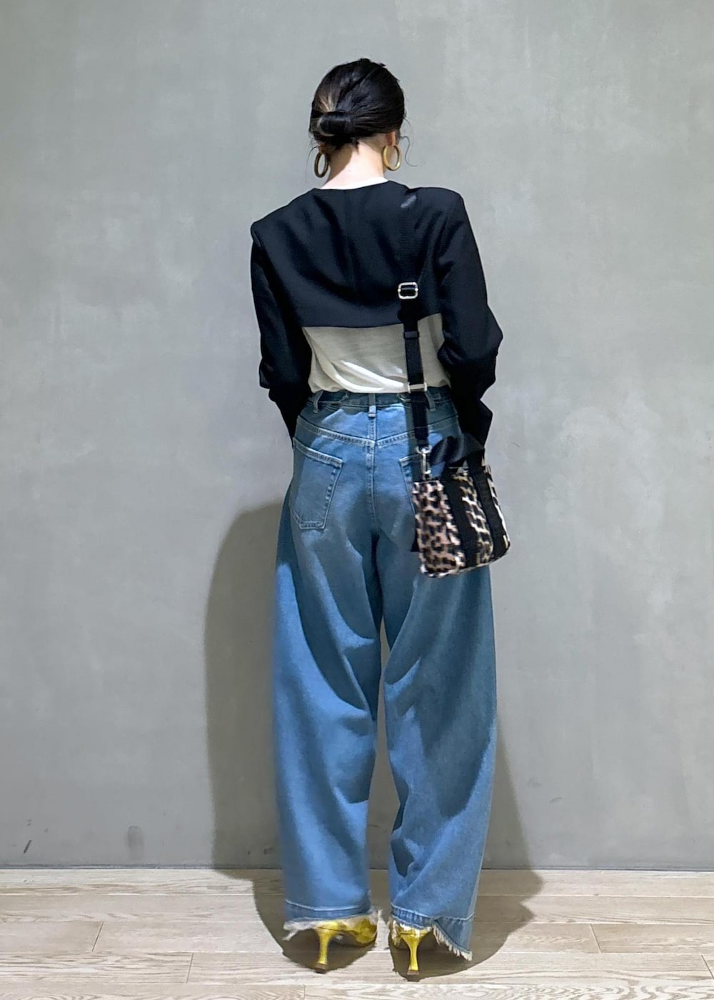 ブルー系のデニムパンツ、ゴールド系のパンプス、ブラック系のノーカラージャケットを着用したレディースの秋コーディネートの3枚目の写真