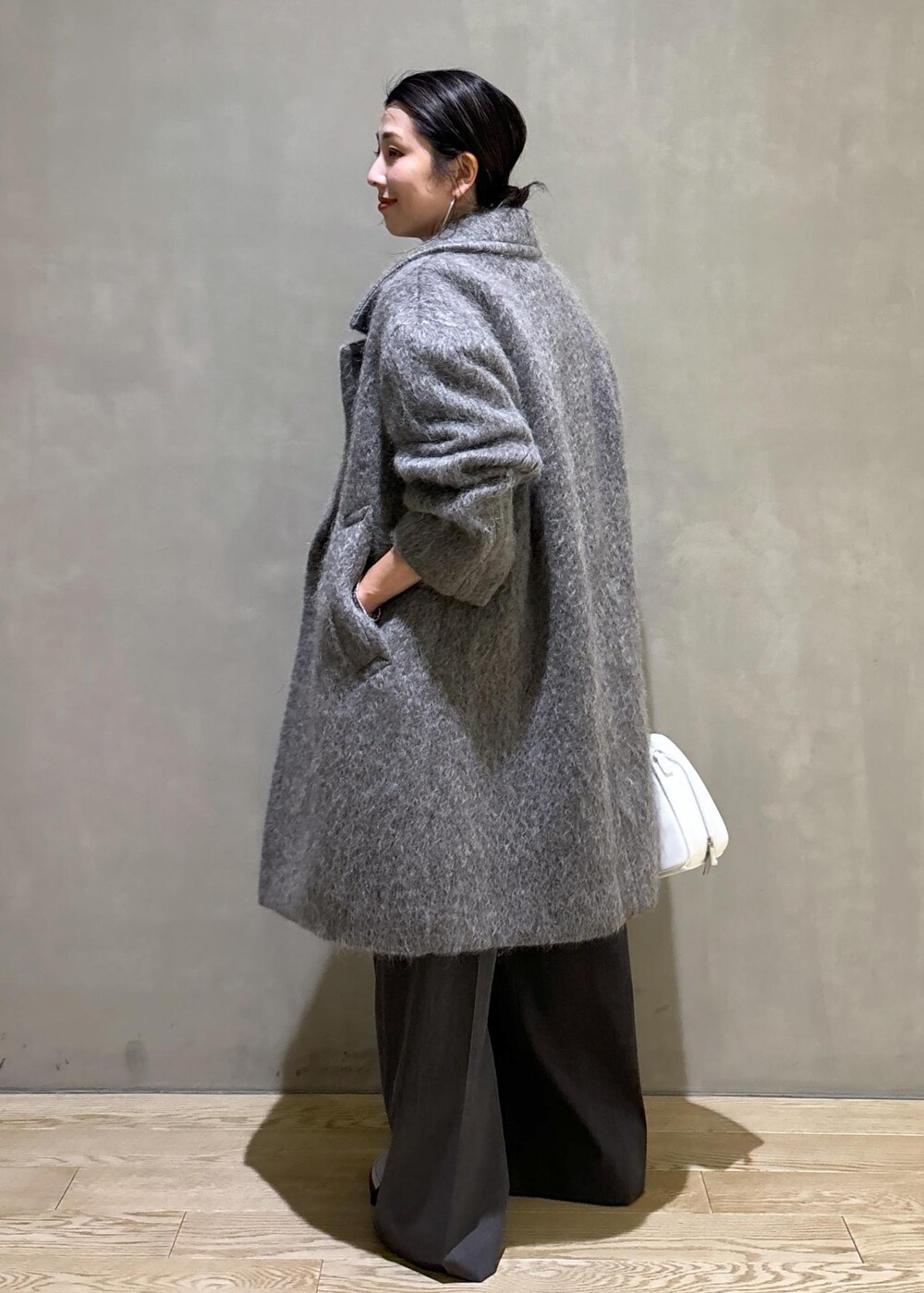 ホワイト系のボストンバッグ、グレー系のカーディガン/ボレロ、グレー系のチェスターコートを着用したレディースの秋コーディネートの4枚目の写真