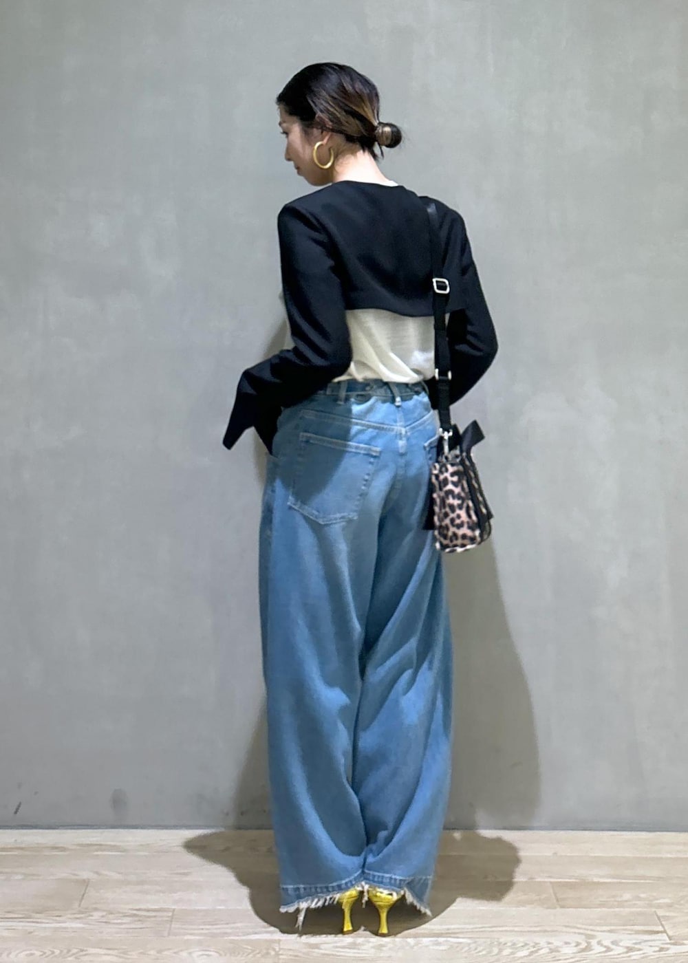 ブルー系のデニムパンツ、ゴールド系のパンプス、ブラック系のノーカラージャケットを着用したレディースの秋コーディネートの4枚目の写真