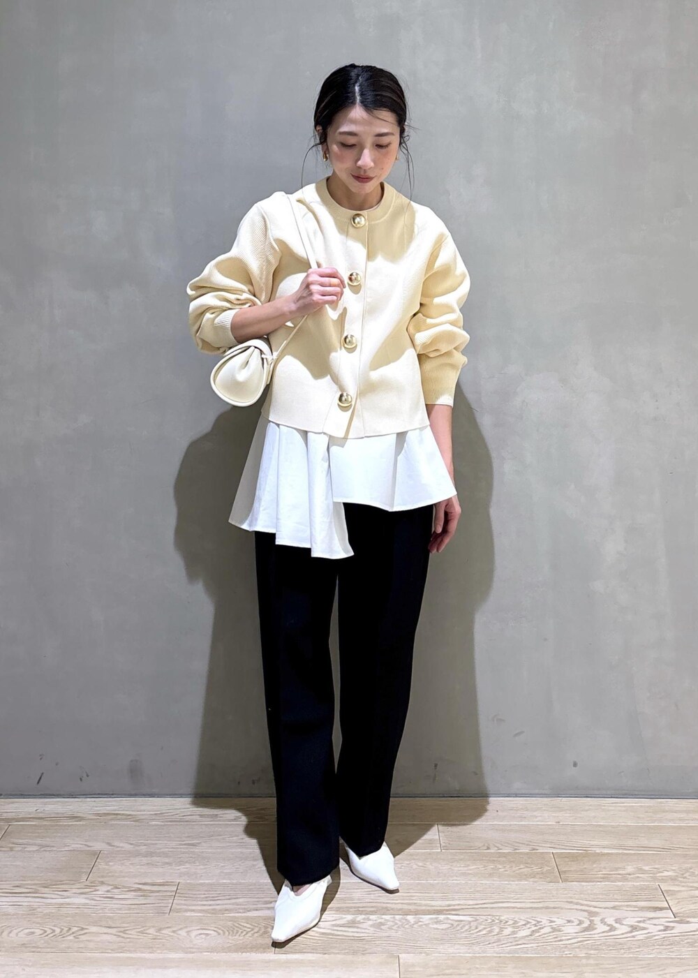 ホワイト系のパンプス、ブラック系のスラックス、ホワイト系のショルダーバッグを着用したレディースの冬コーディネートの6枚目の写真