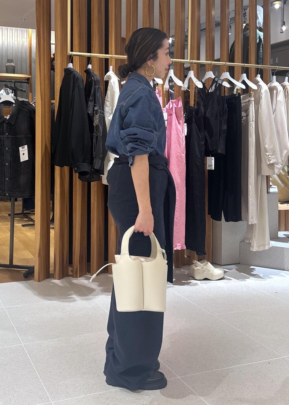 ブラック系のローファー、ホワイト系のハンドバッグ、ブルー系のブルゾンを着用したレディースの春コーディネートの3枚目の写真