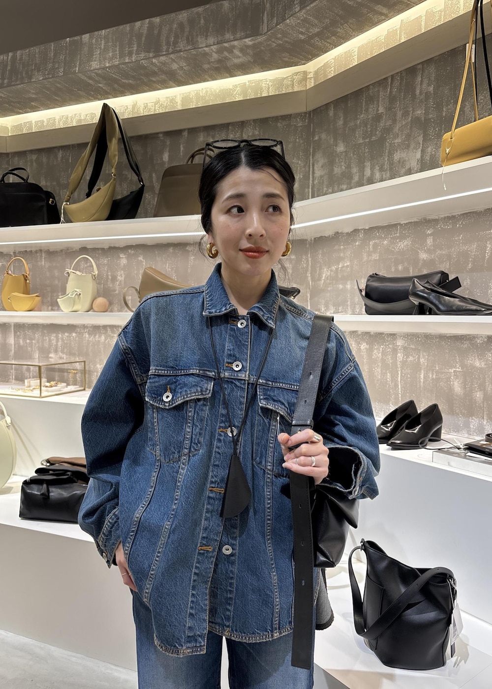 ブルー系のデニムジャケット、ブラック系のショルダーバッグ、ブルー系のデニムパンツを着用したレディースの春コーディネートの10枚目の写真