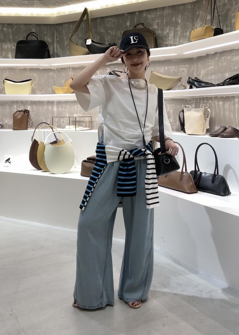 ブルー系のデニムパンツ、ブラック系のショルダーバッグ、ブルー系のTシャツ/カットソーを着用したレディースの春コーディネートの5枚目の写真
