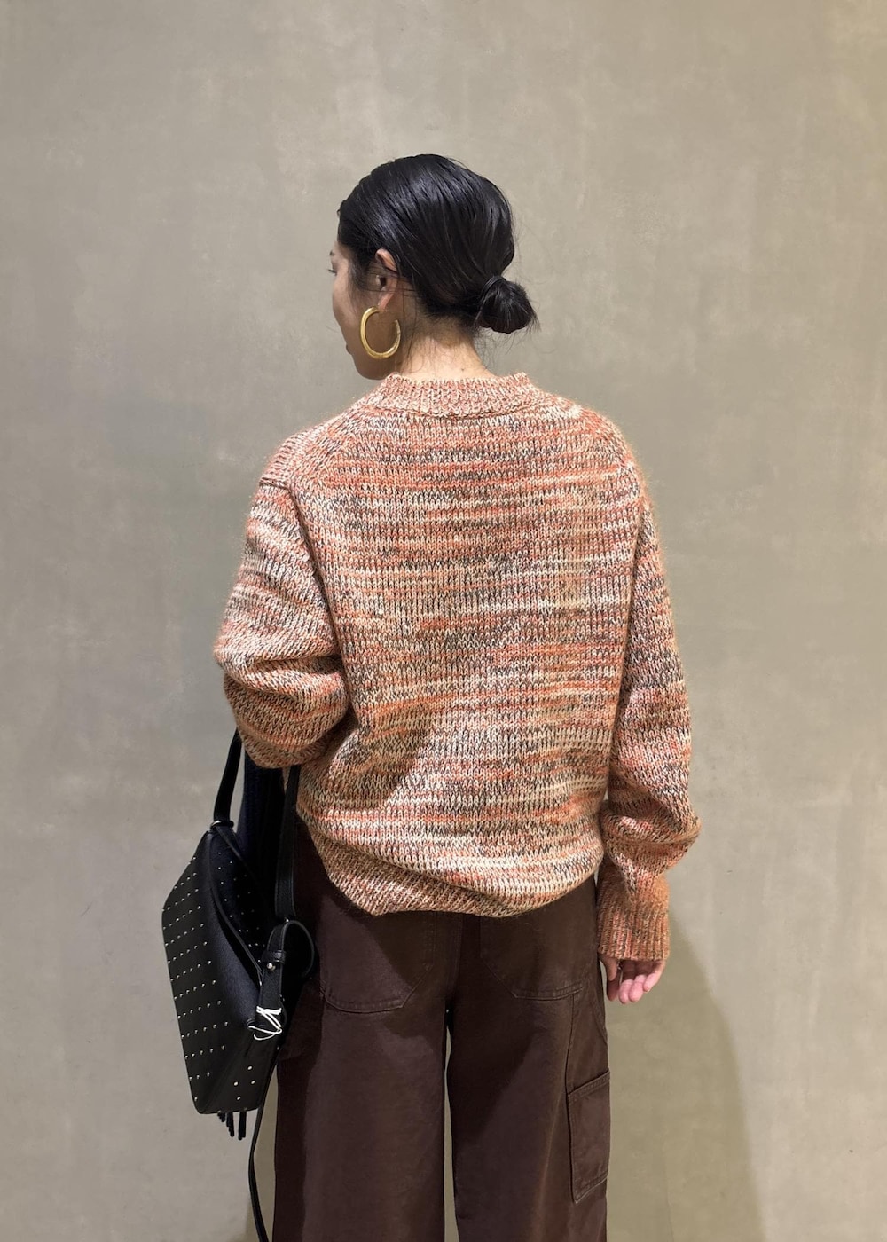 オレンジ系のニット/セーター、ブラック系のショルダーバッグ、ブラウン系のその他パンツを着用したレディースの秋コーディネートの6枚目の写真