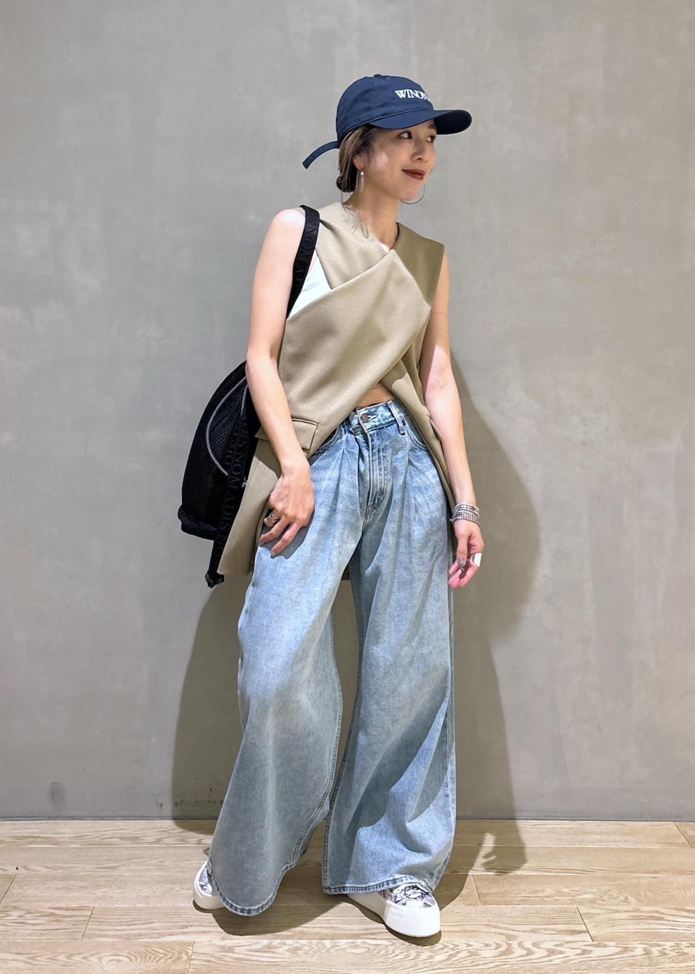 ベージュ系のベスト、ブラック系のスニーカー、ブラック系のショルダーバッグを着用したレディースの夏コーディネートの3枚目の写真