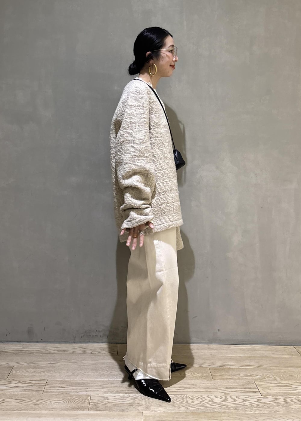 ブラック系のサンダル、ホワイト系のデニムパンツ、ブラック系のショルダーバッグを着用したレディースの冬コーディネートの9枚目の写真