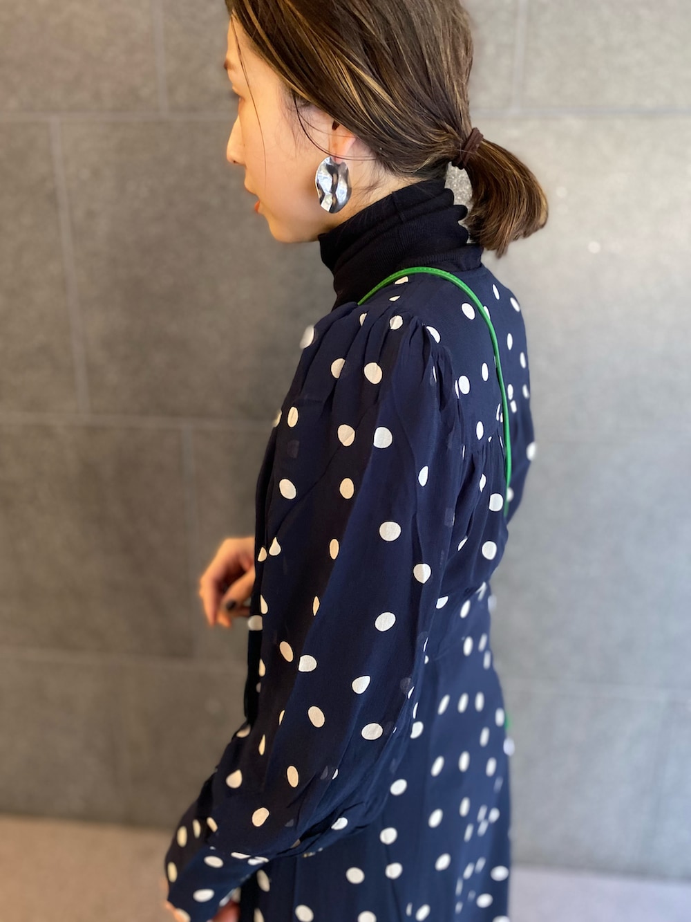 グリーン系のショルダーバッグ、ブルー系のワンピース、ブラック系のブーツを着用したレディースの春コーディネートの2枚目の写真