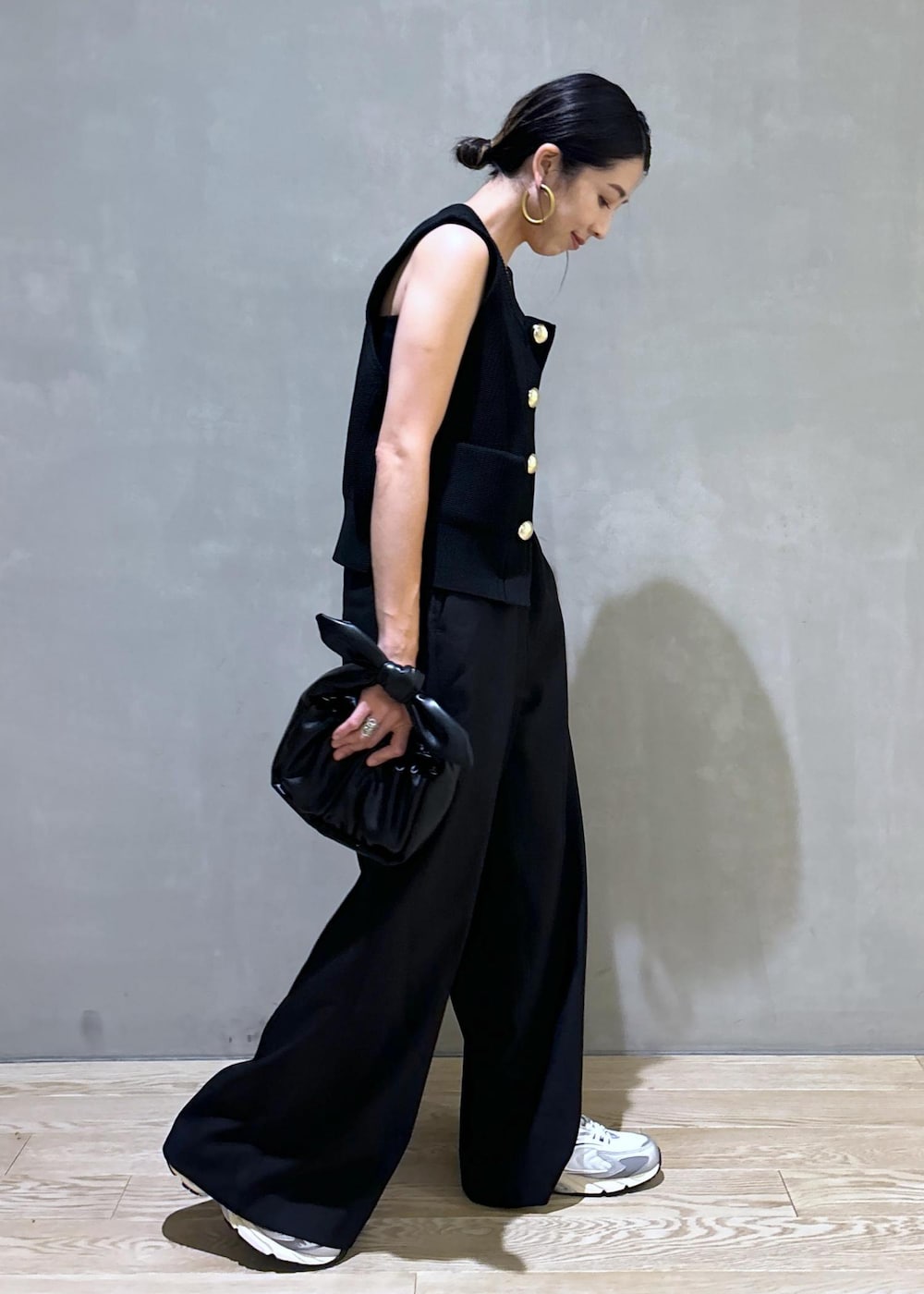 シルバー系のスニーカー、ブラック系のニット/セーター、ブラック系のショルダーバッグを着用したレディースの夏コーディネートの5枚目の写真