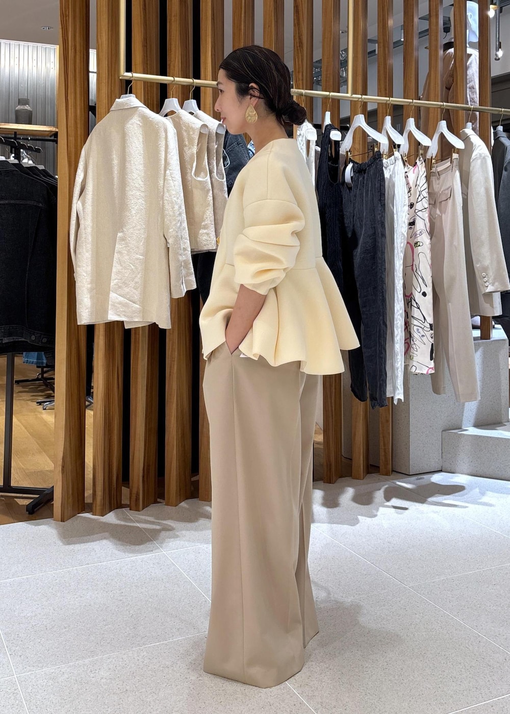 ブラック系のショルダーバッグ、ホワイト系のパンプス、ベージュ系のスラックスを着用したレディースの冬コーディネートの3枚目の写真