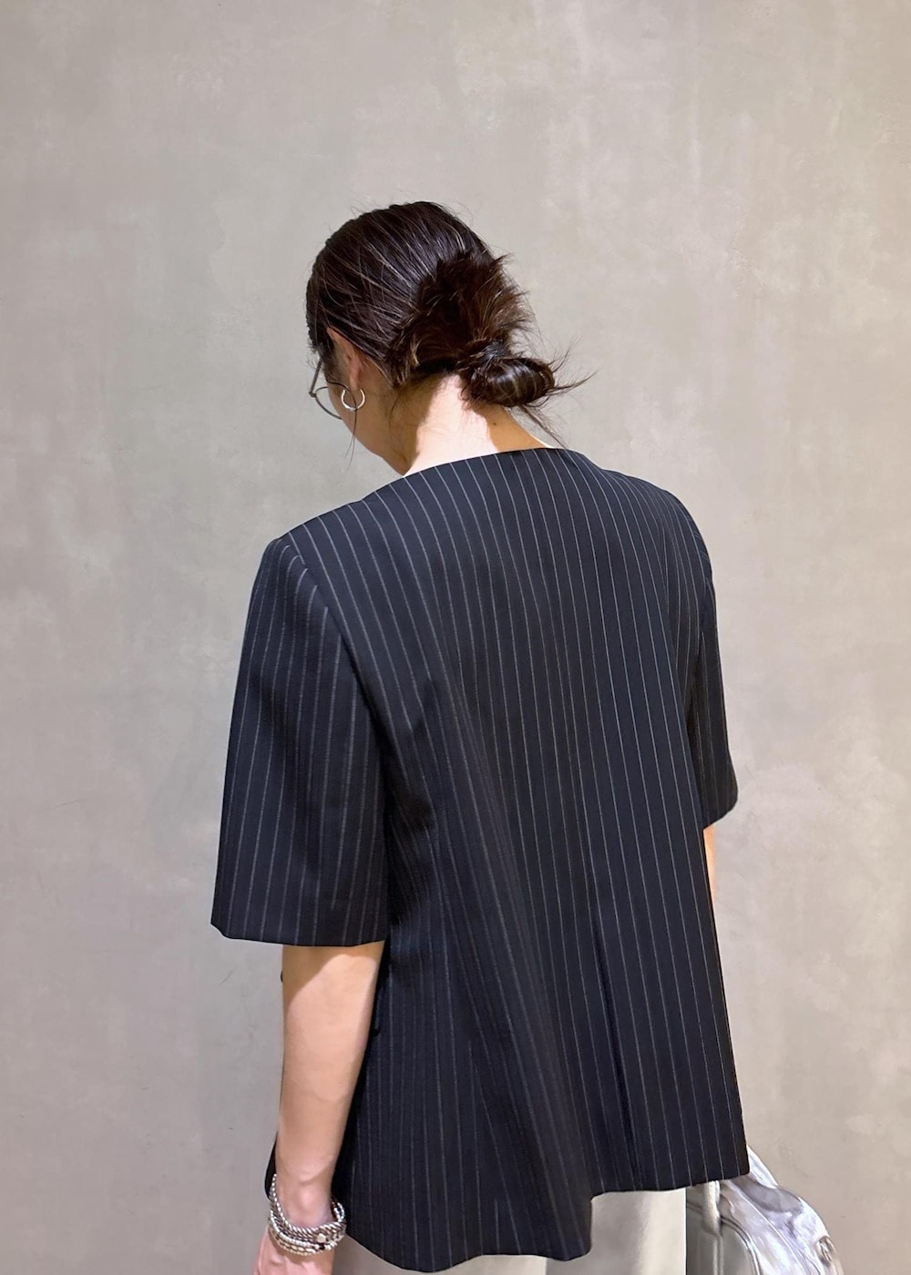 ブルー系のデニムパンツ、ブラック系のノーカラージャケット、シルバー系のボストンバッグを着用したレディースの春コーディネートの10枚目の写真