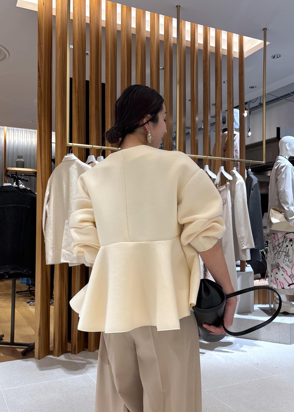 ブラック系のショルダーバッグ、ホワイト系のパンプス、ベージュ系のスラックスを着用したレディースの冬コーディネートの8枚目の写真