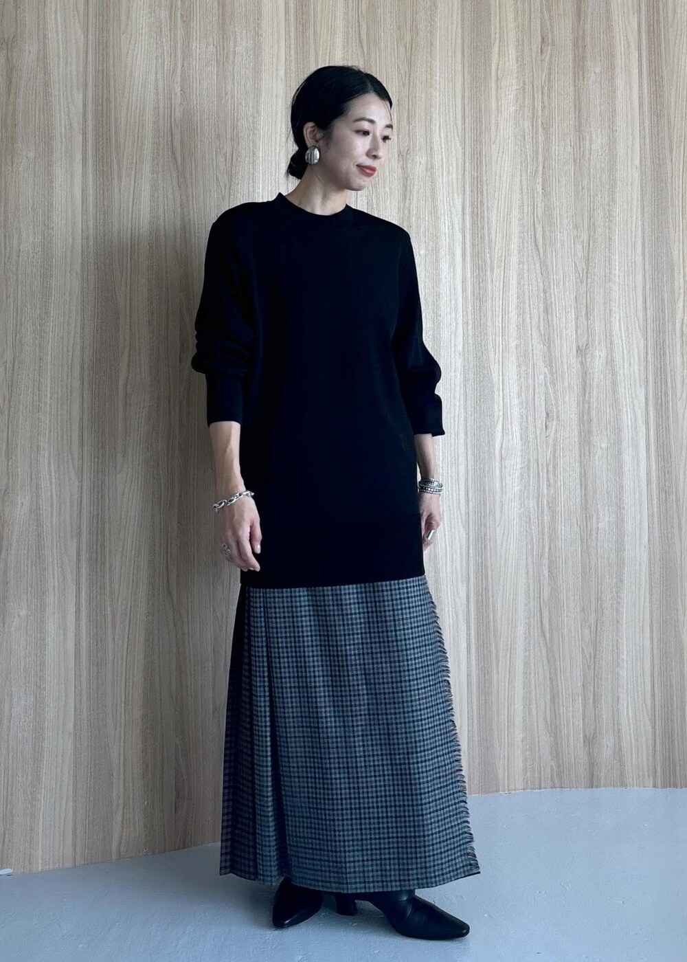 グレー系のスカート、ブラック系のブーツ、ブラック系のニット/セーターを着用したレディースの秋コーディネートの4枚目の写真