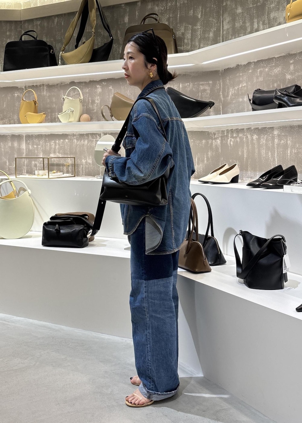 ブルー系のデニムジャケット、ブラック系のショルダーバッグ、ブルー系のデニムパンツを着用したレディースの春コーディネートの9枚目の写真