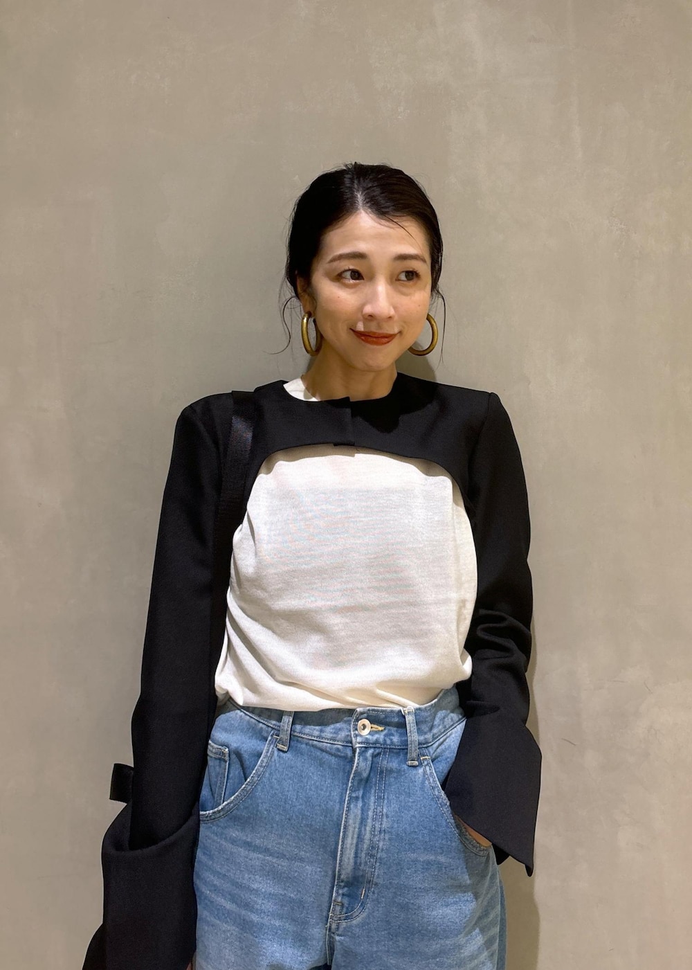 ブルー系のデニムパンツ、ゴールド系のパンプス、ブラック系のノーカラージャケットを着用したレディースの秋コーディネートの7枚目の写真