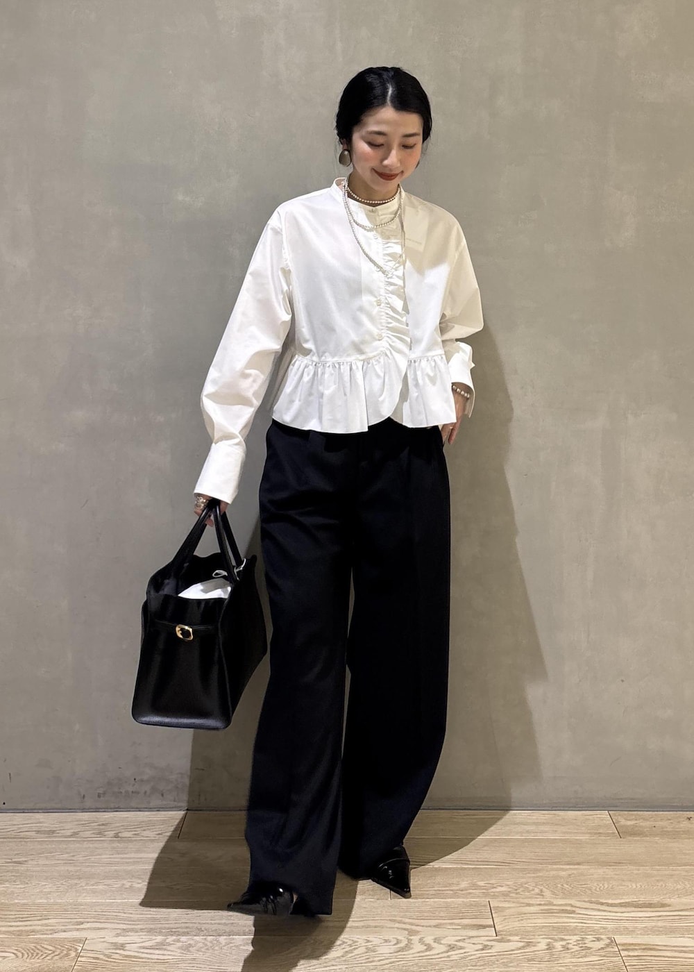 ホワイト系のシャツ/ブラウス、ブラック系のスラックス、ブラック系のトートバッグを着用したレディースの冬コーディネートの2枚目の写真