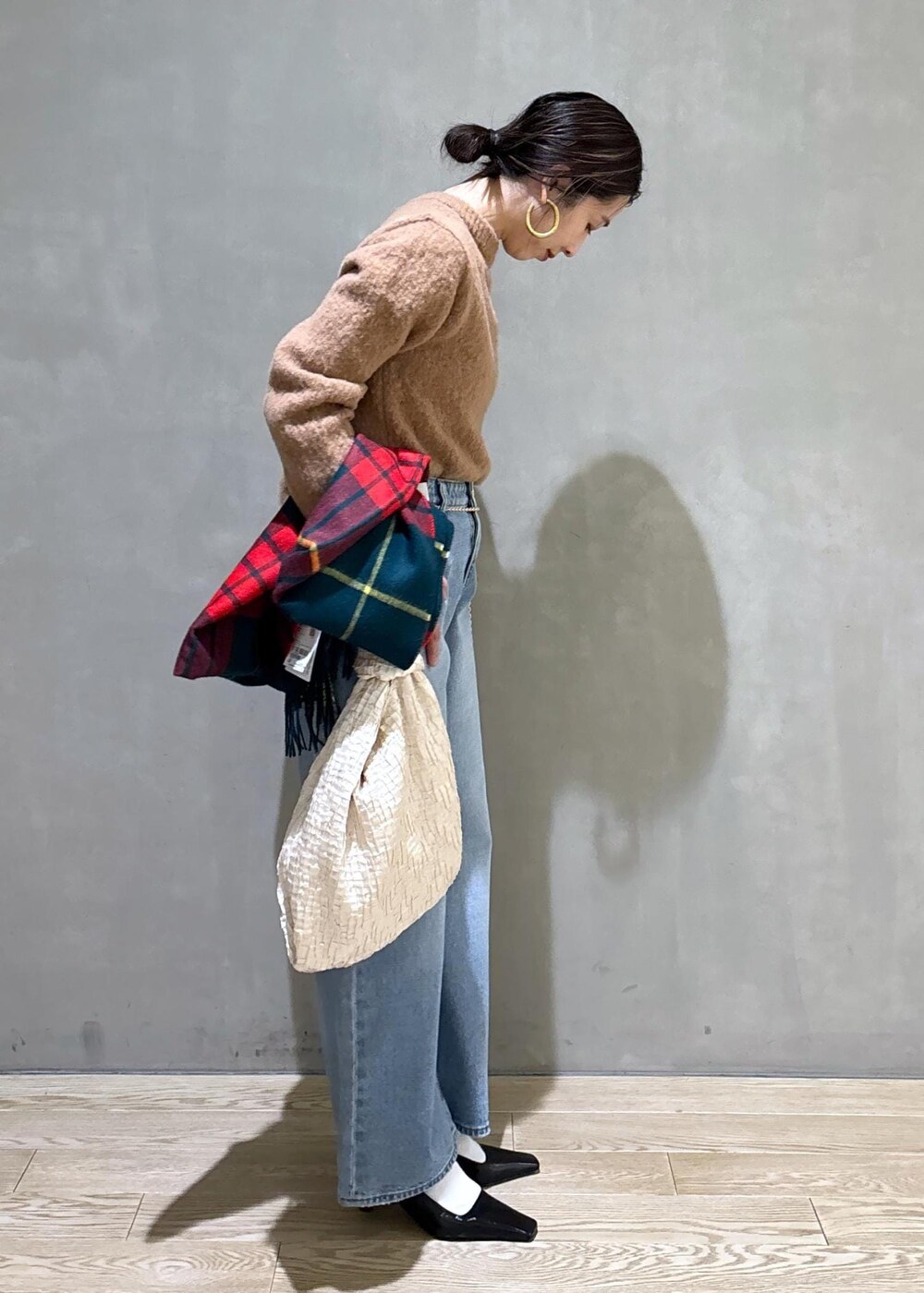 ホワイト系のハンドバッグ、ゴールド系のショルダーバッグ、ブルー系のデニムパンツを着用したレディースの冬コーディネートの5枚目の写真