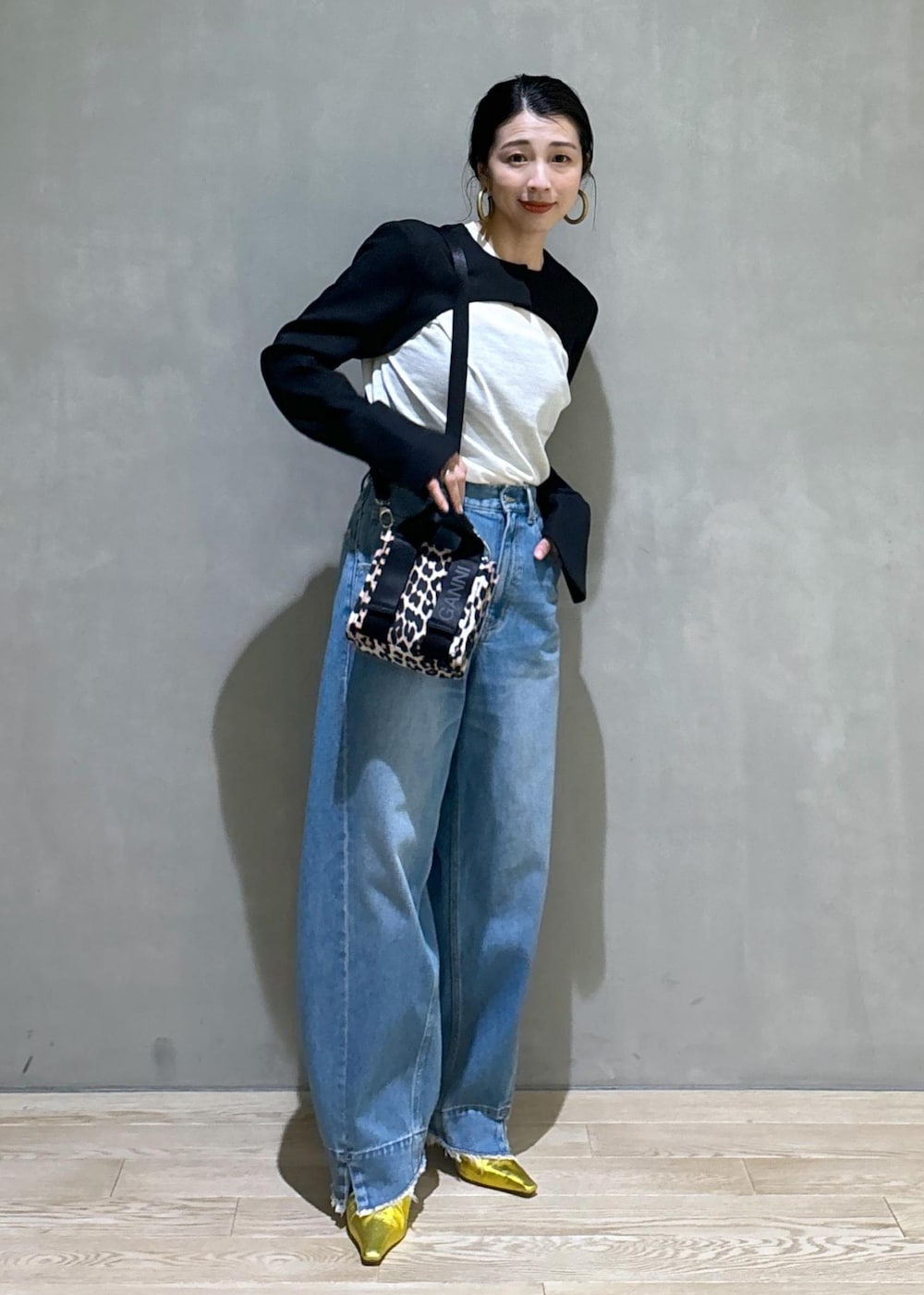 ブルー系のデニムパンツ、ゴールド系のパンプス、ブラック系のノーカラージャケットを着用したレディースの秋コーディネートの5枚目の写真