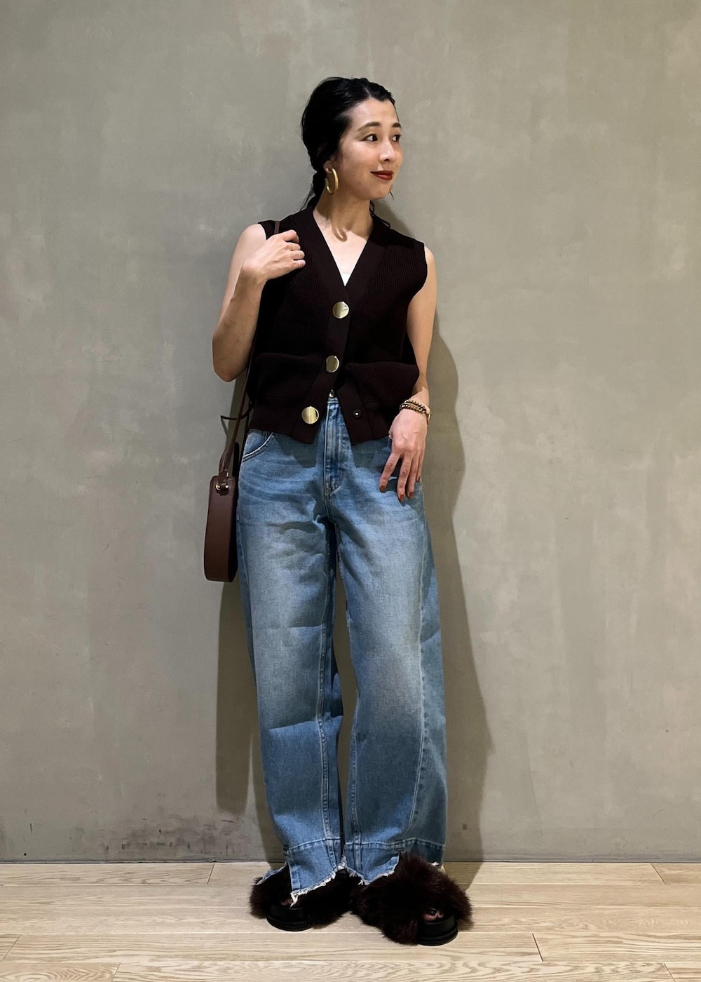ブルー系のデニムパンツ、ブラウン系のサンダル、ブラウン系のベストを着用したレディースの夏コーディネートの2枚目の写真